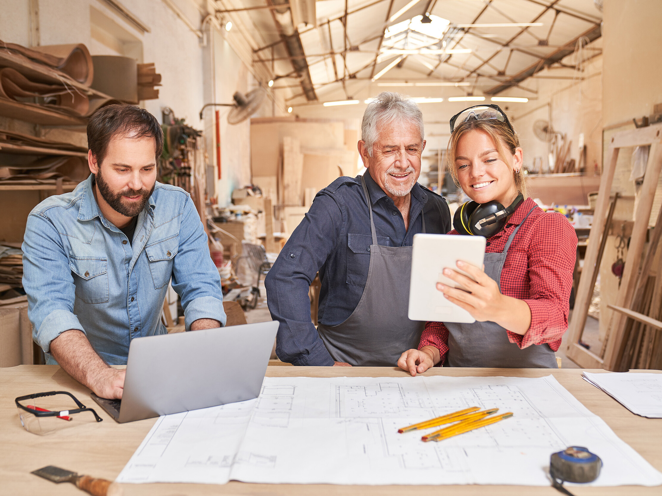 Handwerker in der Werkstatt mit Tablet und Laptop