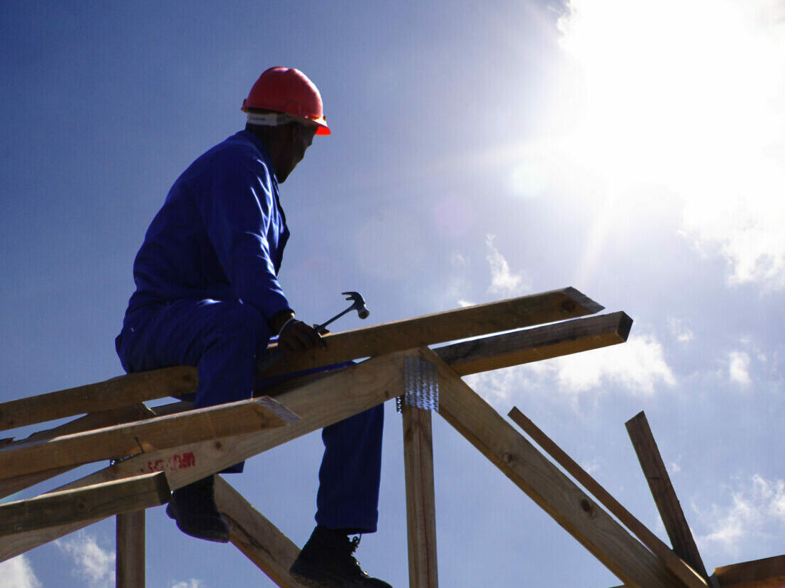 Dachhandwerker sitzt auf Dachstuhl